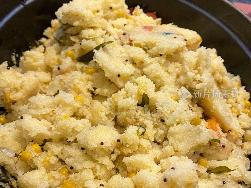 全框架图像的印度早餐食谱的美味rava upma(粗麦粉)在烤箱证明的服务盘，芥末种子，酥油，切碎的洋葱，姜，青椒，柠檬汁，甜玉米，甜椒，腰果，香菜叶，高架视图